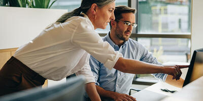 two people in conversation, pointing at a laptop